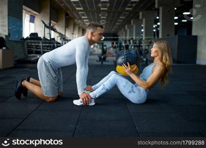 Slim couple doing exercise with ball, training in gym. Athletic man and woman on workout in sport club, active healthy lifestyle, physical wellness. Couple doing exercise with ball, training in gym