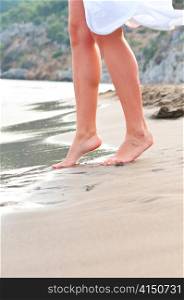 slim female legs steps to the sea