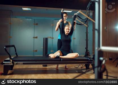 Slim girl in sportswear and instructor, pilates training with ball on exercise machine in gym. Fitness workuot in sport club. Athletic female person, aerobics indoor, body stretching. Girl and instructor, pilates training in gym