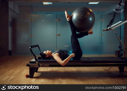 Slim girl in sportswear, pilates training with ball on exercise machine in gym. Fitness workuot in sport club. Athletic female person, aerobics indoor, body stretching. Girl in sportswear, pilates training with ball