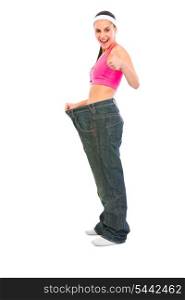 Slim girl pulling oversize jeans and showing thumbs up. Weight loss concept