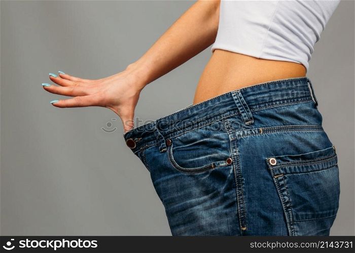 Slim girl trying on large size old jeans