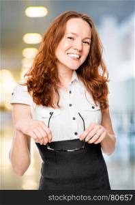 slim secretary with red hair holds glasses in hands