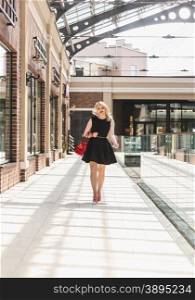 Slim sexy woman in short black dress walking at shopping mall