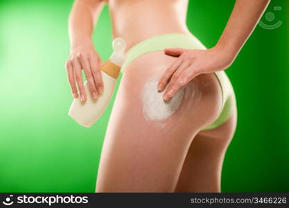 Slim tanned woman body applying cellulite cream on bottom