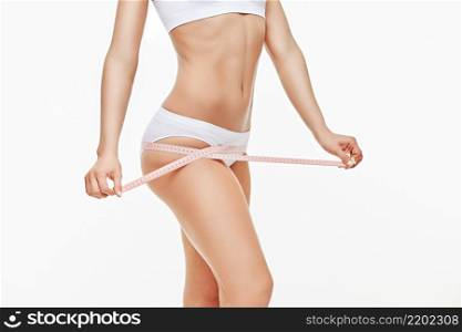 Slim tanned woman&rsquo;s body isolated on white background - waist measurement.. Slim tanned woman&rsquo;s body isolated on white background - waist measurement