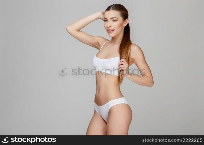 Slim tanned woman’s body Isolated over gray background. Slim tanned woman’s body over gray background