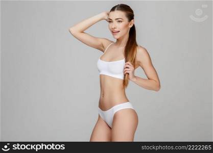 Slim tanned woman’s body Isolated over gray background. Slim tanned woman’s body over gray background