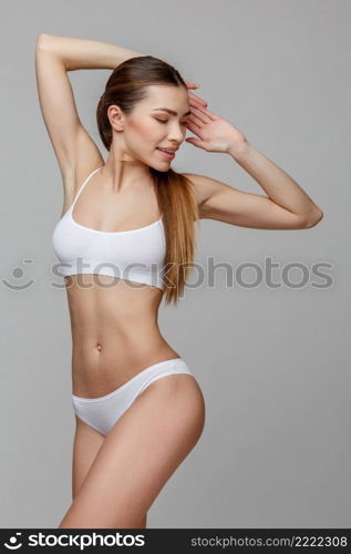 Slim tanned woman’s body Isolated over gray background. Slim tanned woman’s body over gray background