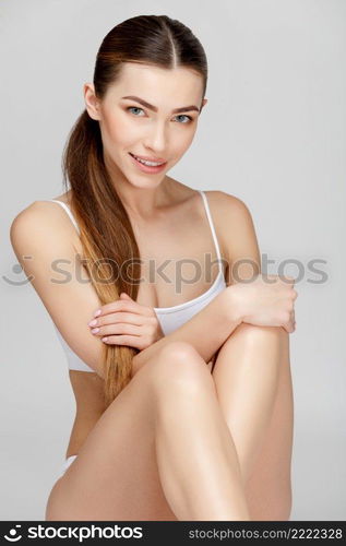 Slim tanned woman’s body Isolated over gray background. Slim tanned woman’s body over gray background