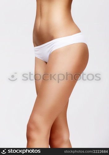 Slim tanned woman’s body Isolated over gray background. Slim tanned woman’s body over gray background