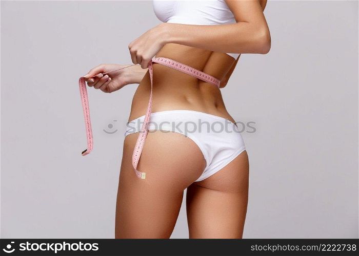 Slim tanned woman’s body Isolated over gray background. Slim tanned woman’s body over gray background