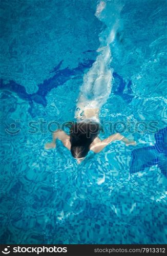 Slim woman covered in long white fabric swimming underwater at pool