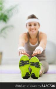 Slim woman doing leg stretching exercises. Focus on sneakers