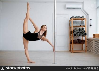 Slim woman on pole-dancing training in class. Girls with perfect body shows excellent stretching. Professional female dancers exercising in gym, pole dance. Slim woman on pole-dancing training in class