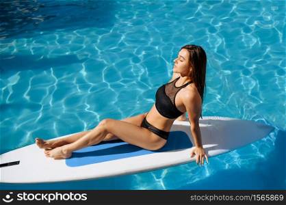 Slim woman swimming on board in the pool on resort outdoors. Beautiful girl relax at the poolside in sunny day, summer holidays of attractive female person. Slim woman swimming on board in the pool outdoors
