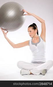 Slim young woman exercising with fitness ball from sitting position