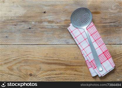 slotted spoon and kitchen towel on rustic wooden background.. slotted spoon and kitchen towel on rustic wooden background