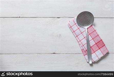 slotted spoon and kitchen towel on rustic wooden background.. slotted spoon and kitchen towel on rustic wooden background