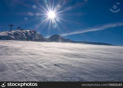 Slovakia. Winter ski resort Jasna. Bright sun in the blue sky over the mountainside and snowy drift. Bright Sun Over the Mountain Slope and Snowy Blizzard