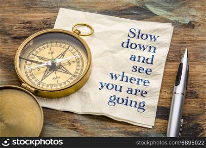 Slow down and see where you are going - inspiraitonal handwriting on a napkin with an antique brass compass