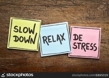 slow down, relax, de-stress concept - motivational lifestyle reminders on colorful sticky notes against rustic wood