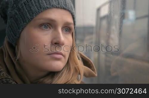 Slow motion and close-up shot of a woman staring through the wet window in the bus. Girl with sad and frustrated face expression. Lonely traveling in the big city