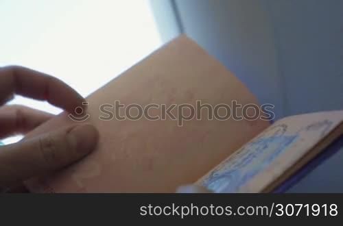 Slow motion and close-up shot of woman looking through the passport with stamps. Traveling marks