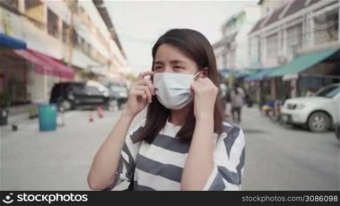 SLOW motion, asian young female take mask off on the street side, covid-19 corona, healthcare concept, Day time, new normal life 2020, protective medical mask, hot weather, high body temperature