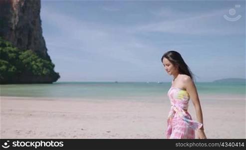 Slow motion, attractive young asian woman in colorful beachwear walking along asia coastline during a hot day, summer solo trip on beach, weekend activity, exploring world, tropical paradise island