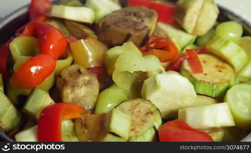 Slow motion close-up shot of a cooking delicious vegetarian dish. Female hand stirring vegetables with plastic spoon in stewpan