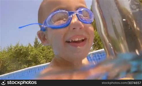 Slow motion close-up shot of a little boy in goggles diving in the swimming pool. Active leisure and recreation