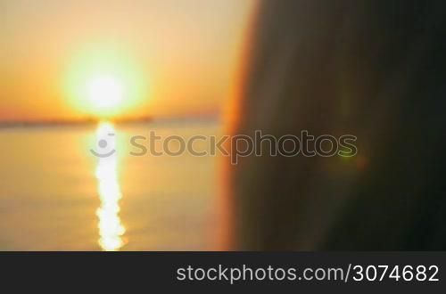 Slow motion close-up shot of a woman blowing soap bubbles, no face can bee seen. Bubbles flying on the background of beautiful sunset over sea