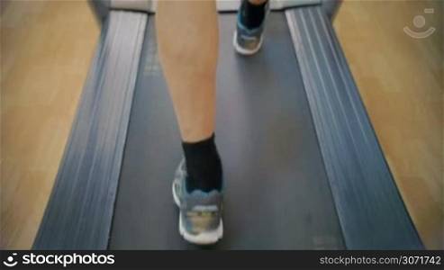 Slow motion close-up shot of male feet walking on treadmill. Every time he coming to the gym he having some cardio