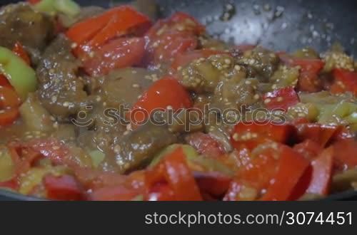 Slow motion close-up shot of pouring soy sauce into the frying-pan with stewed vegetables. Cooking vegetarian dish