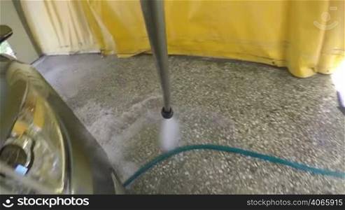 Slow Motion: High pressure washer cleaning car spraying water jet on vehicle surface in garage or washing service centre