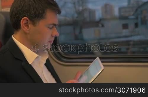 Slow motion of a businessman traveling by train and working with touch pad. Message typing or internet browsing