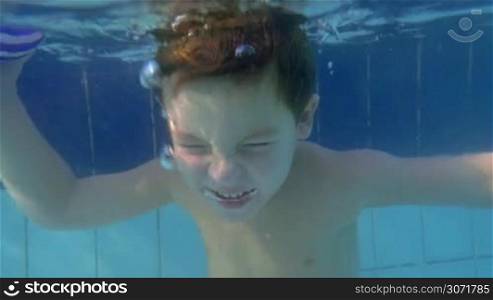 Slow motion of a child diving with open eyes in the pool. Active and brave child