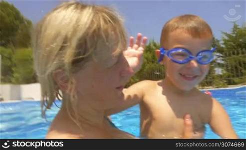 Slow motion of a little boy going underwater from grandmothers hands, he swimming a little and then taking fathers hand in water