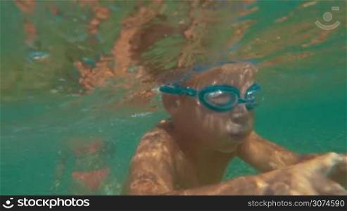 Slow motion of a little boy in goggles diving. He swimming underwater and then happy and proud father taking him in arms
