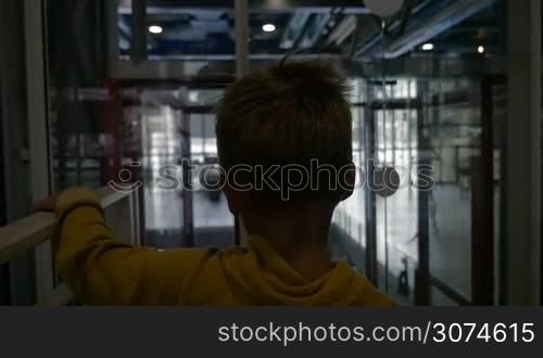 Slow motion of a little boy riding in glassy lift and then leaving it holding mothers hand. Modern buildings