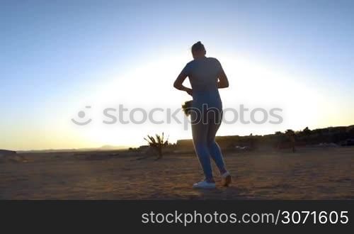 Slow motion of a mother spinning the son around on the beach against bright evening sunlight. Happy family vacation