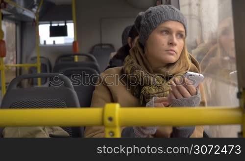 Slow motion of a young girl using smart phone during bus ride. She looking out the window with sad and thoughtful eyes expression