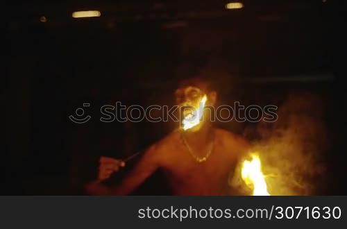 Slow motion of Asian man eating fire. Breath-taking and risky night performance