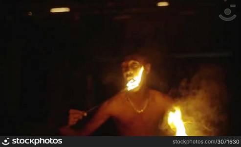 Slow motion of Asian man eating fire. Breath-taking and risky night performance