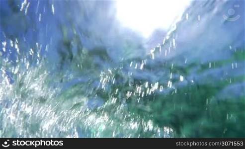 Slow motion of bright midday sun reflecting on wavy water surface and making it sparkling.