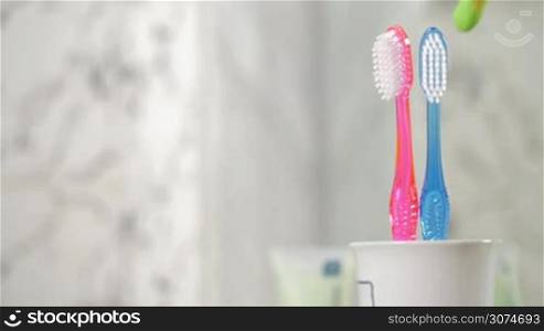 Slow motion of childrens toothbrush appearing with two ones of adults. Concept of a baby birth in the family