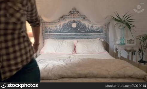 Slow motion of excited young couple jumping on vintage style bed in the hotel room. Happy time together