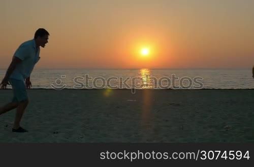Slow motion of father and son running to each other on the beach and then dad spinning him on the background of sunset and sea