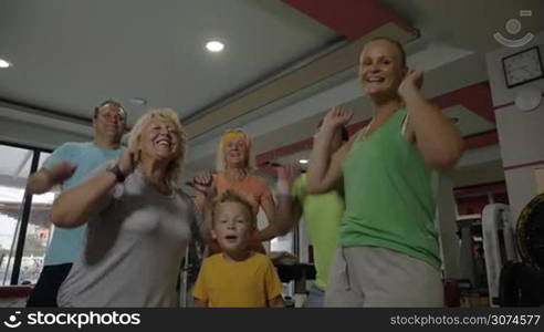 Slow motion of happy family in the fitness center. Child, senior and young people showing excitement after training together and motivating to keep fit with sport